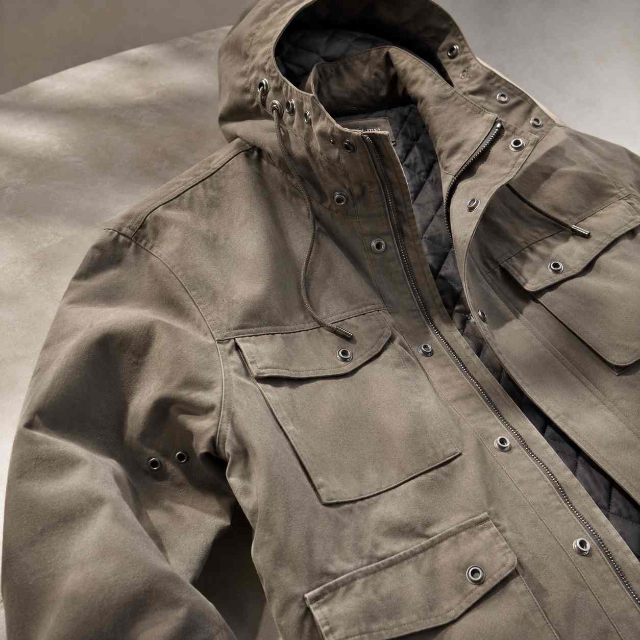 cloth eyelets, Cloth eyelets are installed around the hood, pockets, sleeves and front closure of a brown outdoor jacket.
